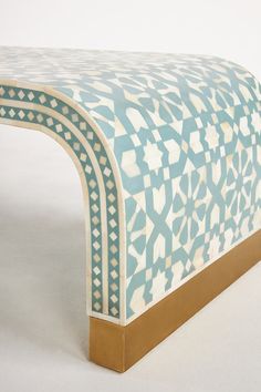 a blue and white bench with an intricate design on the top, against a white background