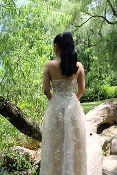 a woman in a white dress looking at trees