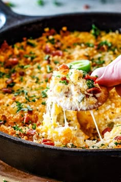 a person is dipping some food into a skillet with broccoli and cheese