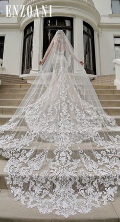 a woman in a wedding dress with a veil on her head is walking down some steps