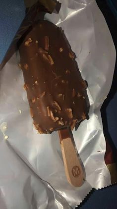 an ice cream with nuts on top sits in a wrapper