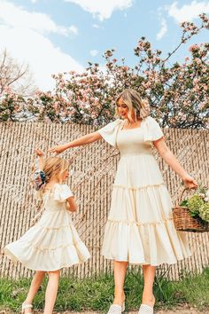 a mother and daughter holding hands while standing in front of a wall