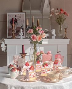 a table topped with plates and cups filled with cake next to a vase full of flowers