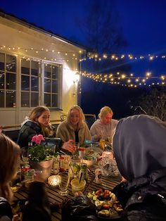 a group of people sitting around a table outside at night