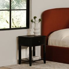 a bedroom with a bed, nightstand and window