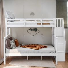 a white bunk bed sitting in a bedroom next to a wooden floor and window with curtains on the windowsill