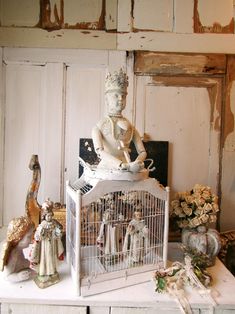 a white birdcage sitting on top of a table filled with figurines