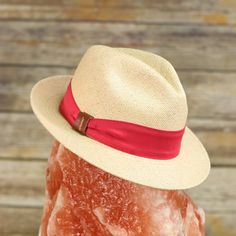 A modern take on the classic fedora Traveler made with 100% toquilla straw and pink or red hatband with leather bow detailing. This effortless piece can easily be worn year-round. The quality can be seen in the beautifully structured crown and stingy brim. This packable fedora is meant for traveling with you wherever you go whether in a suitcase, a purse, or a beach bag. This item is a genuine Panama hat handwoven in Ecuador and blocked and trimmed in the USA. Imported.Crown: 4 1/4" Center DentM Luxury Fedora Straw Hat For Summer, Luxury Fedora Straw Hat For The Beach, Luxury Summer Straw Fedora Hat, Luxury Brimmed Boater Hat For Summer, Luxury Summer Beach Fedora, Luxury Fedora Straw Hat For Kentucky Derby, Spring Panama Hat With Adjustable Fit And Short Brim, Luxury Brimmed Summer Hats, Adjustable Fedora For Kentucky Derby Travel