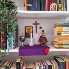 a shelf filled with books and figurines next to a cross on top of it