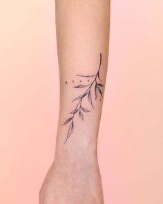 a woman's arm with a small branch tattoo on it