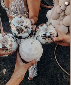 several people holding disco ball ornaments in their hands