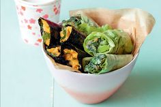 a white bowl filled with lettuce and other vegetables next to a paper cup