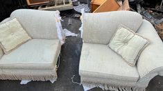 two couches that are sitting next to each other on the ground in front of some junk