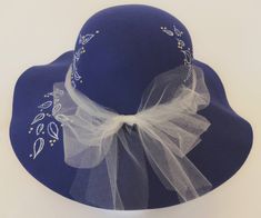 "Hand Painted Women's Wide-Brimmed Hat--\"Deep Blue\" This is a once-wear, disposable hat for those who have an event or need for a hat, but do not wish to wear it longer than that event.  \"Painted Hats\" offers few short-wear/disposable hats just for this type of wearing style.   You will be stunning in this gorgeous deep blue hat with white and cream accent designs, plus a cream netting bow. The wide-brimmed hat is lovely for that feminine look of attention to the eye line.  The felt-like material is firm enough to hold the brim nicely with just a bit of wave to avoid looking \"stiff\".  Embellishing the hat are several areas around the crown and down on the brim of climbing white and blue abstract leaves plus pearl-like \"dots\" in cream.  To finish the hat, a light netting material is Blue Felt Hat With Short Brim For Beach, Blue Brimmed Felt Hat For Kentucky Derby, Blue Cloche Hat With Curved Brim, Blue Wide Brim Hat One Size, Blue Wide Brim Sun Hat One Size, Womens Wide Brim Hats, Abstract Leaves, Painted Hats, Blue Hat