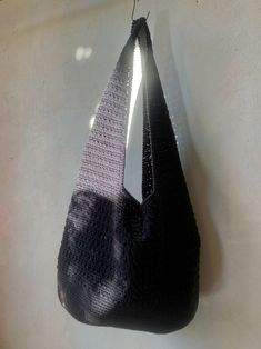 a black purse hanging from the side of a wall next to a white wall with sunlight coming through it