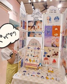 a woman standing in front of a booth with stickers on it's walls