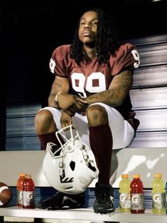 a man sitting on top of a bench with a football helmet in front of him