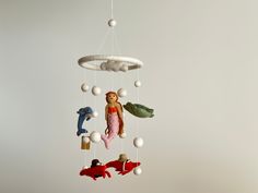 a mobile with toys hanging from it's sides in the shape of fish and mermaids