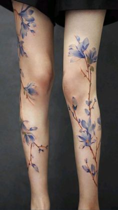 a woman's legs with blue flowers painted on them and the bottom part of her leg