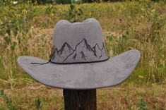 Mountain scene meticulously crafted and hand- burned into this adjustable cowboy hat. This versatile design can be purchased as is, or tailored to your taste with personalized touches. Imagine adding intricate artwork or a layered hat band adorned with flowers, feathers, or stones of your choosing. Our customization process is an artistic journey, with designs drawn freehand, ensuring each hat is a one of a kind unique masterpiece. Prices for additional customization vary depending on the complexity and detail of your desired addition. Upon placing your order, we'll promptly provide you with a quote and commence artwork creation upon receipt of payment. Please note, due to the bespoke nature of customization and our commitment to hygiene standards, this product is non-refundable. Turnaroun Country Style Outdoor Felt Cap, Fitted Outdoor Cap, Fitted Hats With Curved Brim For Outdoor, Fitted Outdoor Hat With Curved Brim, Fitted Curved Brim Hats For Outdoor, Rustic Outdoor Hat, Custom Handmade Hats For Outdoors, Fitted Country Hats For Outdoor, Handmade Outdoor Cap