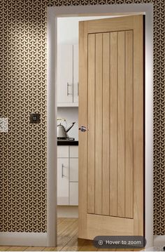 an open wooden door in a kitchen next to a wall with black and white designs