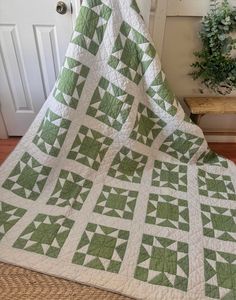 a green and white quilt sitting on top of a wooden floor next to a door