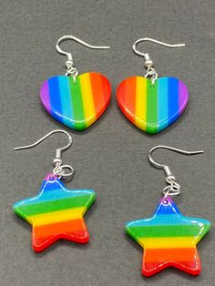 These bright colorful rainbow heart and star earrings are a must have for any fashionista  Each star or heart dangles from a hypoallergenic hook Lightweight  Each star is approximately 1 inch by 1 inch  Each heart is approximately 1 inch by 1 inch 3 options to choose from  Rainbow colored hearts  Rainbow colored stars  Rainbow heart and star mix ( 1 star & 1 heart) Jewelry Making Business, Football Earrings, Colored Earrings, Retro Candy, Earrings Star, Scene Outfits, Dragon Earrings, Angel Wing Earrings, Black Rainbow