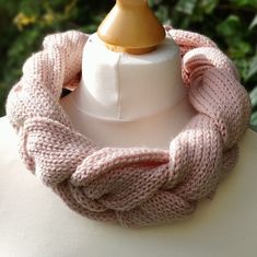 a white mannequin with a pink knitted scarf around it's neck