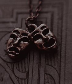 two skull heads are attached to a chain on a piece of wood that has been carved into it