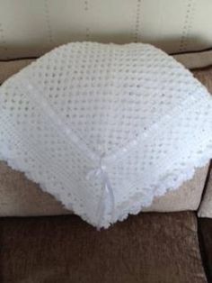 a white crocheted pillow sitting on top of a brown couch