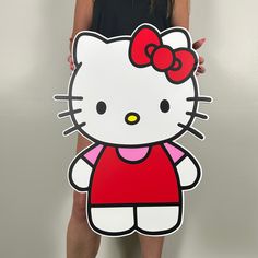 a woman holding up a cardboard hello kitty cutout