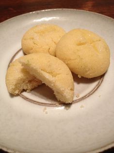 three cookies on a white plate sitting on a wooden table