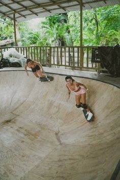 two women riding skateboards on the side of a ramp