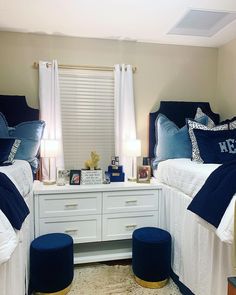 two twin beds with blue and white bedding in a bedroom next to a window