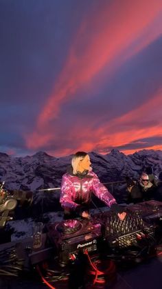 a person sitting on top of a snowmobile in front of some mountains at sunset