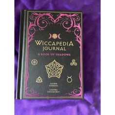 a book on wiccapedia journal sitting on a purple cloth covered tablecloth