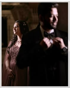 a man in a tuxedo standing next to a woman wearing a dress and bow tie