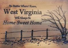 a wooden sign that says, west virginia will always be home sweet home with a tree and fence