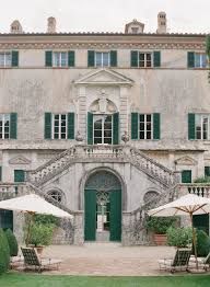 an old building with green shutters and white umbrellas in the front lawn area