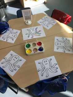 children's artwork is displayed on the table in front of an easel with paint and watercolors