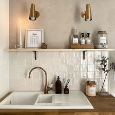 a kitchen with white tile and wooden counter tops, gold faucets and brass fixtures