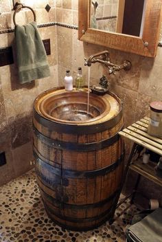 a wooden barrel sink in a bathroom next to a mirror