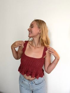 a woman standing in front of a white wall with her hands on her hips and smiling