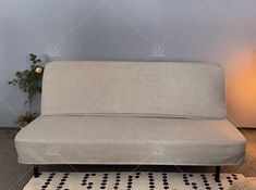 a white couch sitting on top of a rug next to a lamp