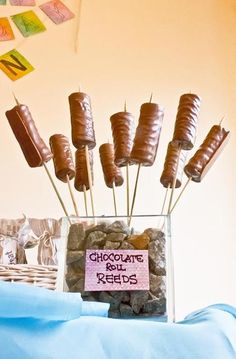 there are chocolates on sticks in a glass vase with rocks and candy bar wrappers