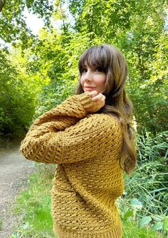 a woman standing in the grass wearing a yellow sweater