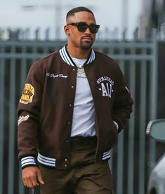 a man walking down the street wearing a jacket with patches on it's sleeves