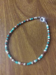 a beaded bracelet with turquoise and white beads on a wooden surface, resting on a table