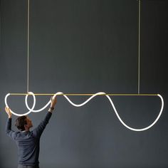 a man is trying to hang something from the ceiling with two wires attached to it