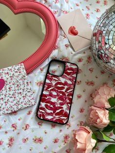 a cell phone case sitting on top of a table next to flowers and a mirror